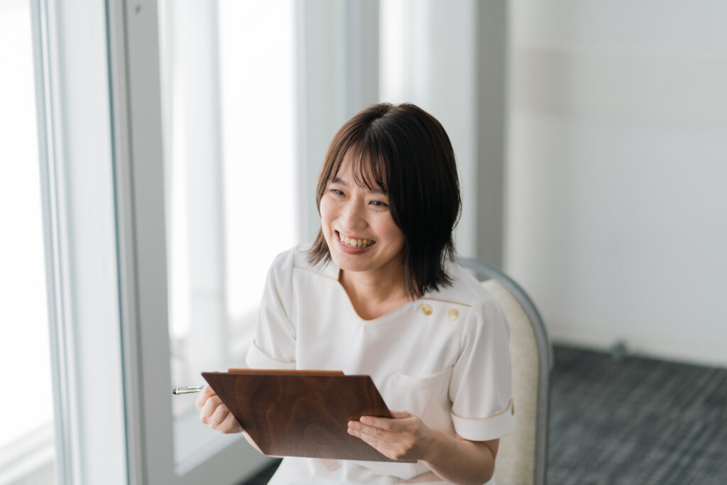 カウンセリングをしている女性セラピスト。落ち着いた空間で、お客様と丁寧に話をしている様子。